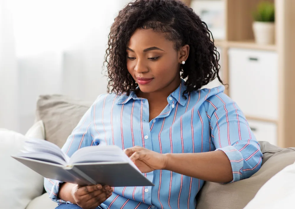 Woman happily reading a self-help book and learning new information about how she can improve her marriage.