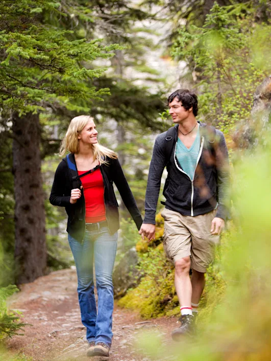 Neurodiverse couple walking on a trail and smiling at each other.