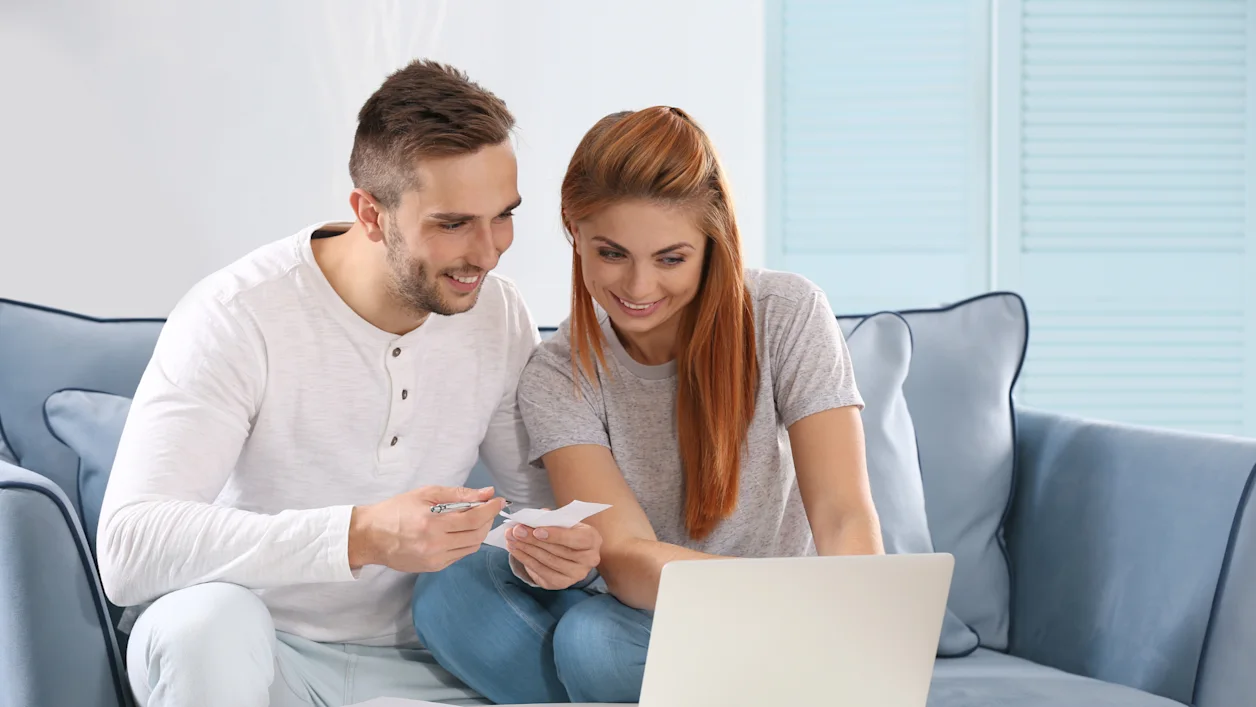 Couple sitting around a computer checking the price of couples therapy. They're glad to have found that it is very reasonable.